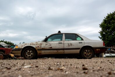 Old rusty abandoned car at scrapyard ready for recycling and disposal